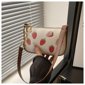 Detail of strawberry print on off-white PU leather bag with gold metal chain