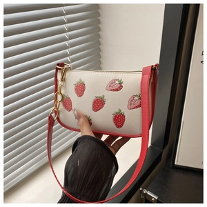 Detail of white PU shoulder bag with red strawberry print and golden metal chain