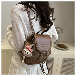 Close-up of canvas backpack featuring IBCMB embroidery and cute plush charm detail