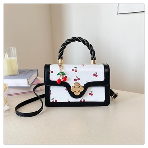 Detail of white cherry print mini bag featuring black twisted handle and gold petal lock