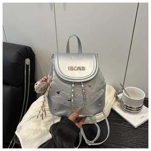 Close-up of silver mini backpack featuring metallic texture and pink IBCMB embroidery