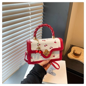 Détail du petit sac carré à motif cerise avec fermoir doré et accessoire de cerise