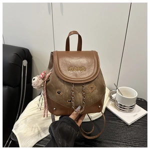 Detail of vintage brown backpack with metallic chain and cute plush bear charm decoration