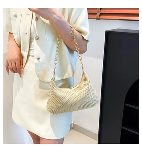 Minimalist handwoven shoulder bag with golden chain strap worn by a model in interior