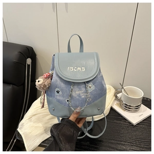 Detail of light blue denim mini backpack with dog embroidery, metal chain and plush charm