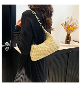 Macro detail of beige handwoven straw shoulder bag with elegant golden chain link strap