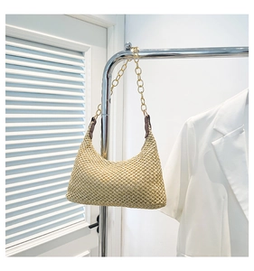 Dettaglio della borsa a spalla intrecciata beige con tracolla a catena dorata e anelli in metallo