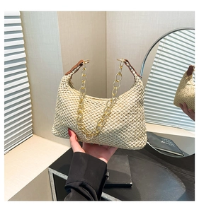 Detail van beige strooien hobo-tas met geweven textuur, acryl ketting en lederen riem