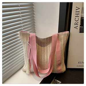 Detail of woven tote bag with pink straps and fringe tassel against a soft light background
