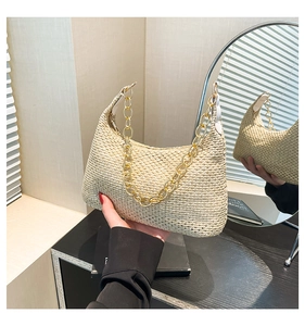 Detail van beige strooien hobo tas met grove gouden ketting en natuurlijke weeftextuur