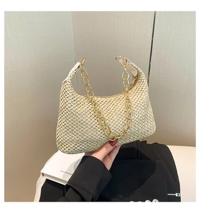 Details van de beige geweven strooien tas met gouden ketting en wit leren handvat riem