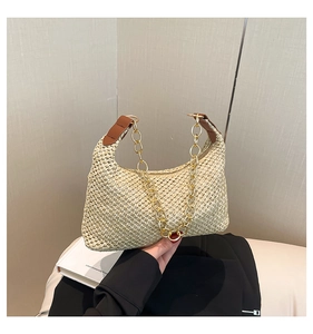 Detail van beige geweven schoudertas met bruin leer en goudkleurige kettingriem