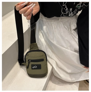Detail of army green nylon crossbody bag featuring front zipper pocket and adjustable strap