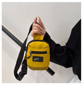 Detail of yellow nylon crossbody bag with black mesh pocket and adjustable shoulder strap