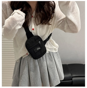 Detail of black nylon chest bag with adjustable strap and decorative logo patch
