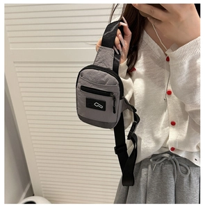 Detail of gray minimalist chest bag showing nylon texture and adjustable strap buckle