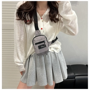 Detail of grey nylon crossbody bag featuring mesh pocket and adjustable strap on a model