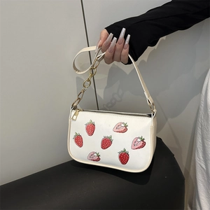 White shoulder bag with strawberry print, featuring a gold chain strap and zipper closure