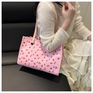 Gros plan du sac cabas rose à motif cerises en similicuir avec poignées renforcées