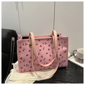 Grand sac fourre-tout rose à motif cerises sur une table avec des accessoires mode