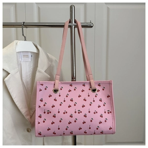 Vue détaillée du sac cabas rose avec imprimé cerise sur un support métallique