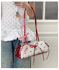 Detail of red bow ribbon and silver heart pendant on white polka dot shoulder bag