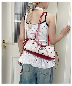 Detail of white baguette bag with red bow patterns, heart charm and balletcore aesthetic