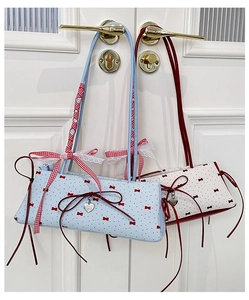 Detail view of contrast color bucket bags with red bows and silver heart charms on a door
