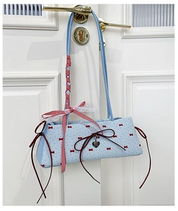 Detail of light blue canvas bag featuring red bow prints and heart shaped metal pendant