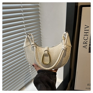 Detail of white crocodile embossed crescent bag with gold ring and braided handle