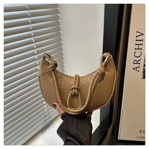 Close-up of khaki half-moon bag with faux crocodile texture and braided handle detail