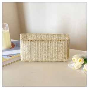 Detail of straw woven clutch bag featuring fine vertical texture and metal buckle closure