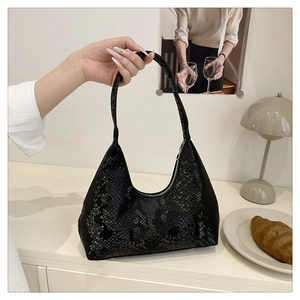 Detail of black snakeskin texture on a hobo bag with zipper on a minimalist table