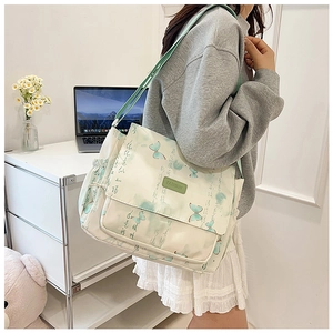 Détail de la sacoche en toile avec motif papillon vert et poche latérale à cordon