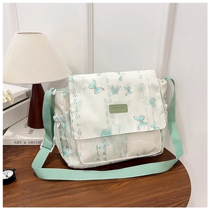 Détail du sac en toile crème avec motifs papillon verts et accents vert menthe clair