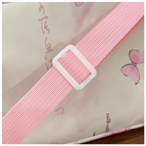 Détail de la bandoulière rose avec boucle réglable blanche et motif papillon