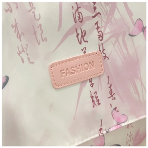 Détail d'un sac beige avec motifs papillon et écusson logo en cuir rose fashion