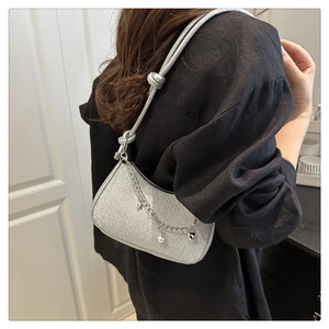 Détail du sac sous le bras à paillettes argentées avec chaîne et breloques étoiles