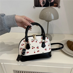 Minimalist white shell handbag with cherry print and black contrast handles and straps