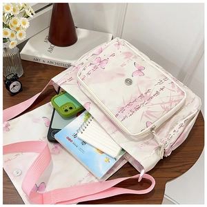 Détail d'un sac bandoulière en toile blanche contenant des carnets et un portable