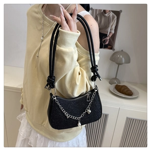 Détail du sac à bandoulière noir brillant avec chaîne argentée, perles et cœurs