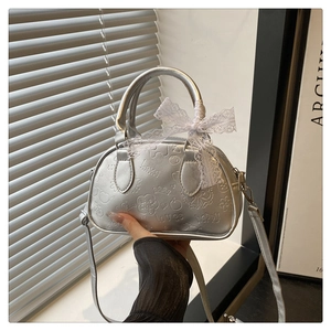 Detail of silver Boston bag with cartoon embossing and a delicate white lace bow