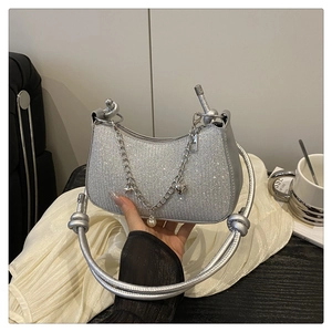 Gros plan d'un sac argenté pailleté avec poignée nouée et breloques étoile et cœur