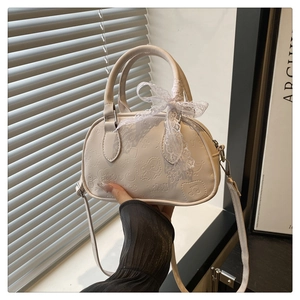 Detailed view of cream PU leather bowling bag with cartoon embossing and lace ribbon bow