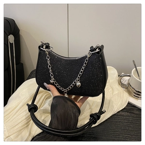 Détail du sac croissant à paillettes noires avec breloques argentées et poignée en cuir