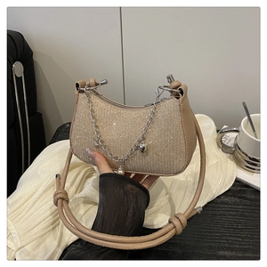 Détail du sac sous le bras or champagne avec strass denses et chaîne argentée à breloques