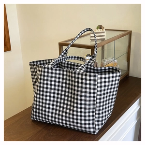 Detail view of large black and white gingham tote bag on a wooden table in a cafe