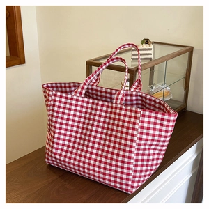 Detail of red and white vichy checkered canvas tote bag with spacious interior for travel