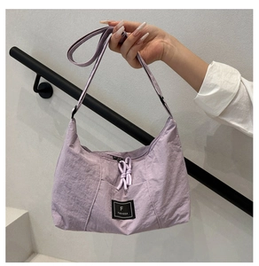 Detail of lilac nylon crescent bag featuring FANNISSA label and knotted zipper puller