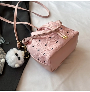 Dettaglio della borsa a secchiello rosa con stampa a fiocco e ciondolo morbido